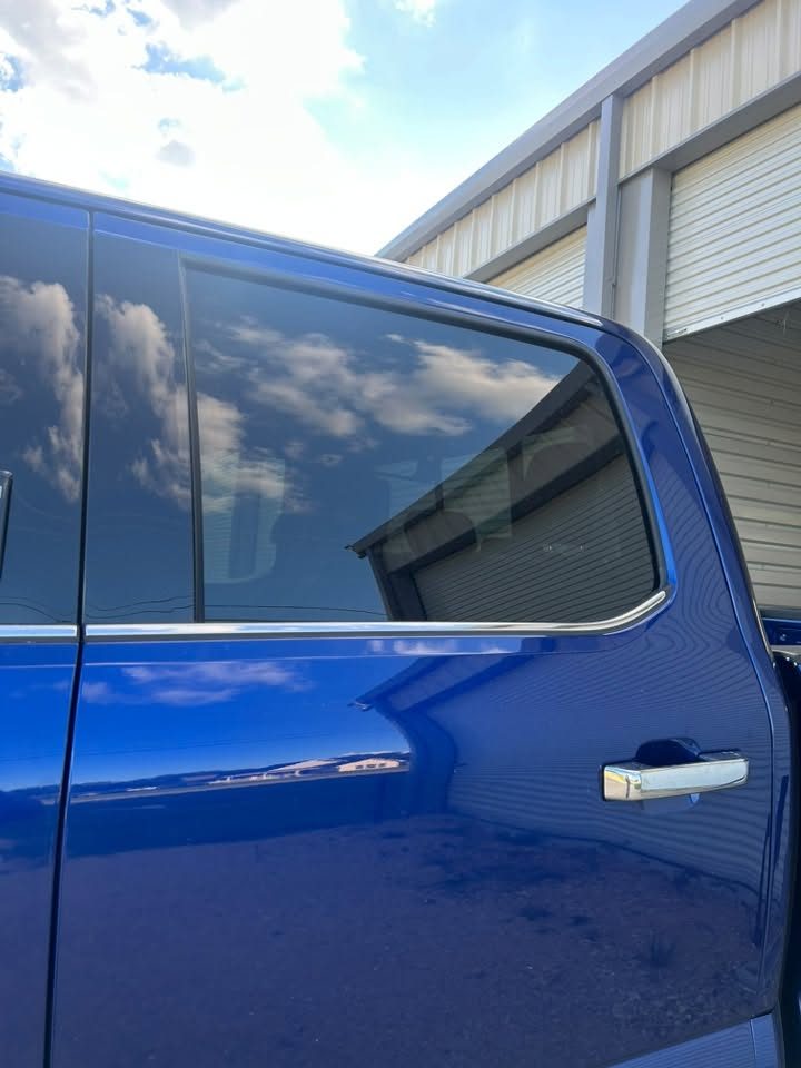 A close-up of a tinted door window on a blue truck